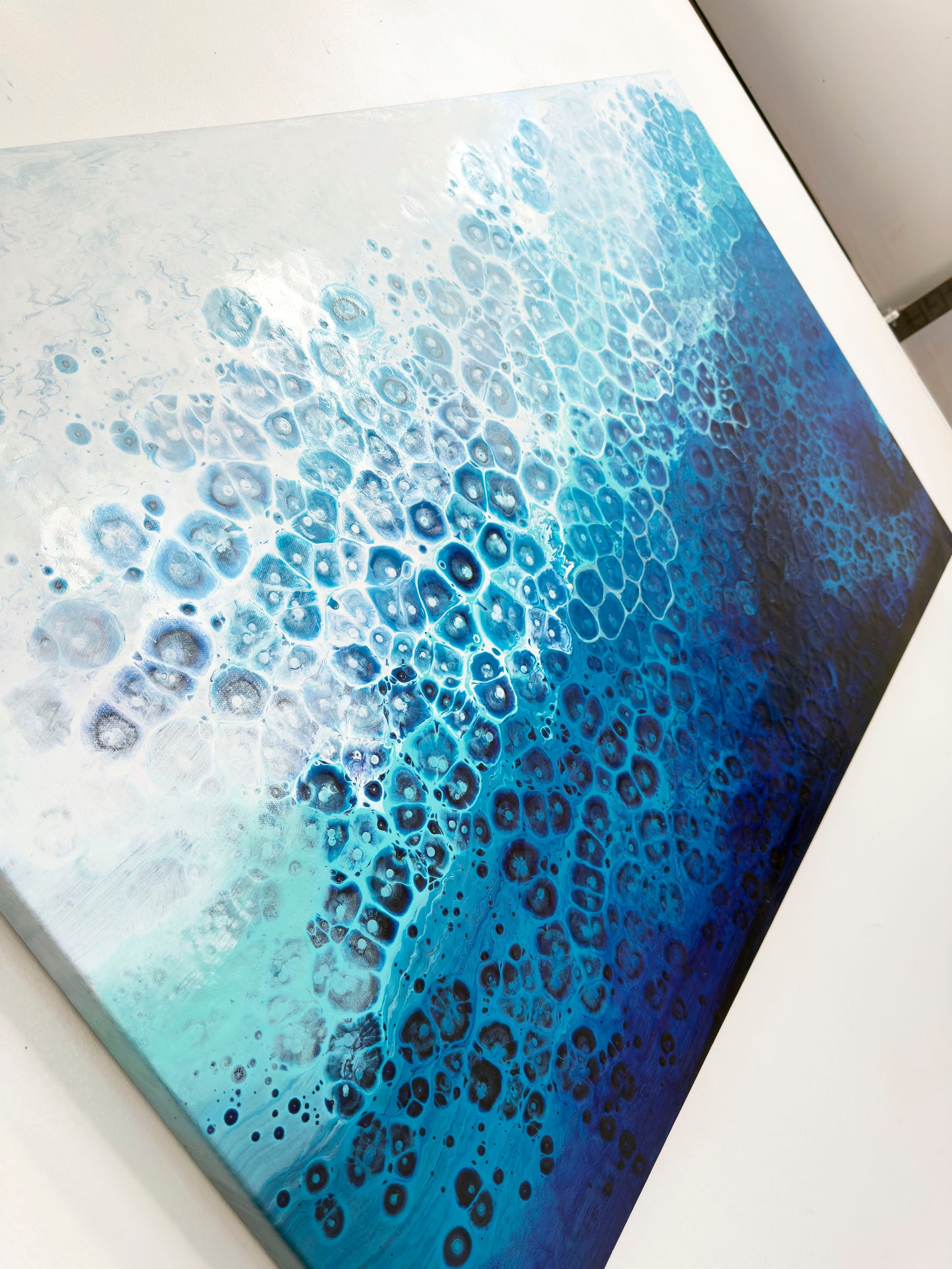 Abstract art piece with blue and white color gradient on a textured surface