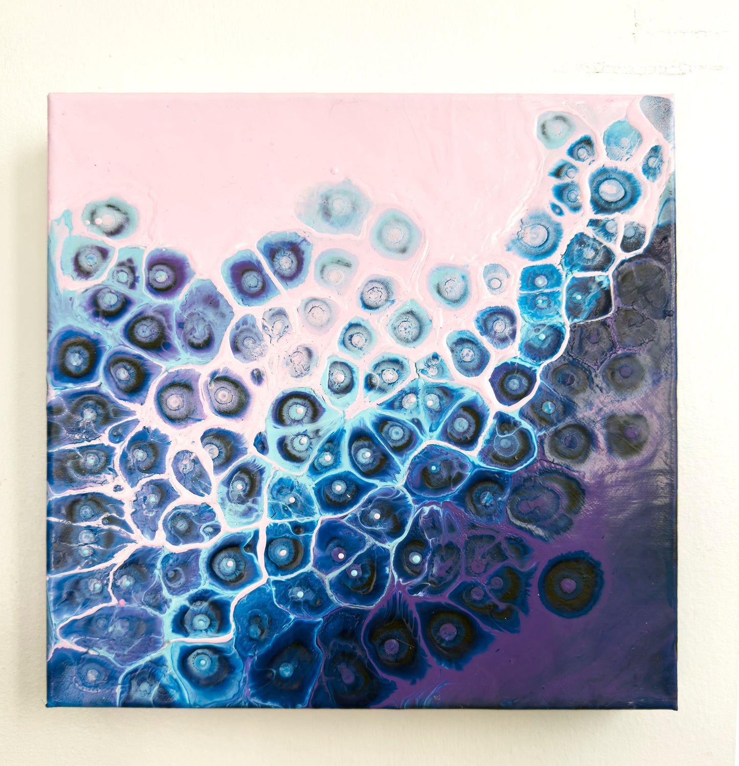 Abstract art piece with blue and purple circular patterns on a pink background