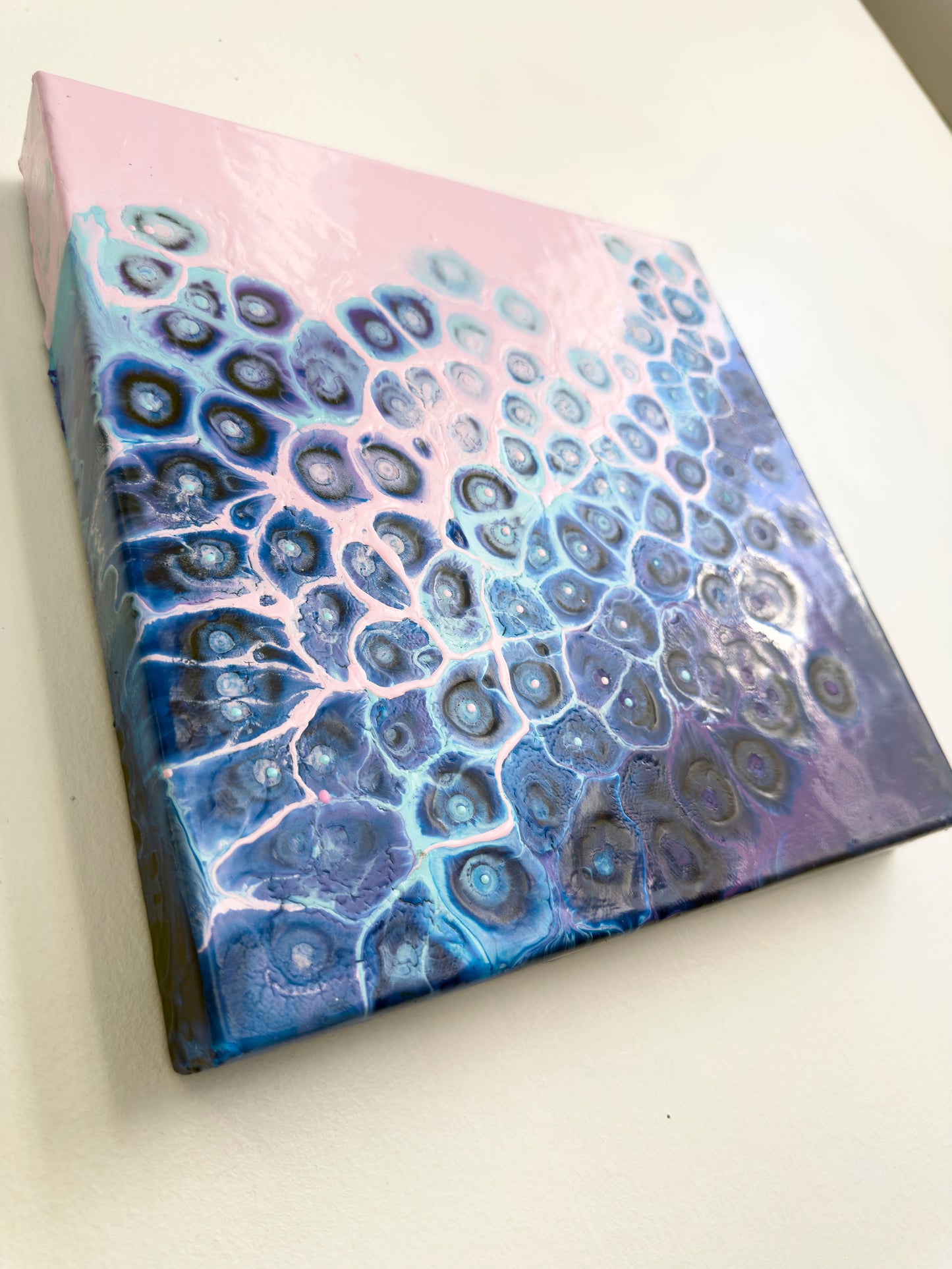 Canvas with a blue and pink abstract pattern on a white surface