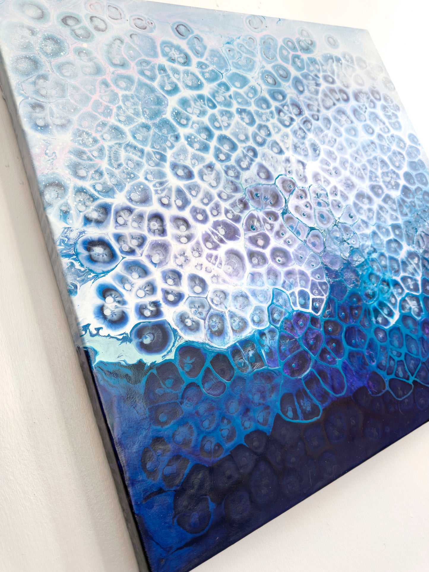 Close-up of a textured blue and white abstract painting with a gradient effect.