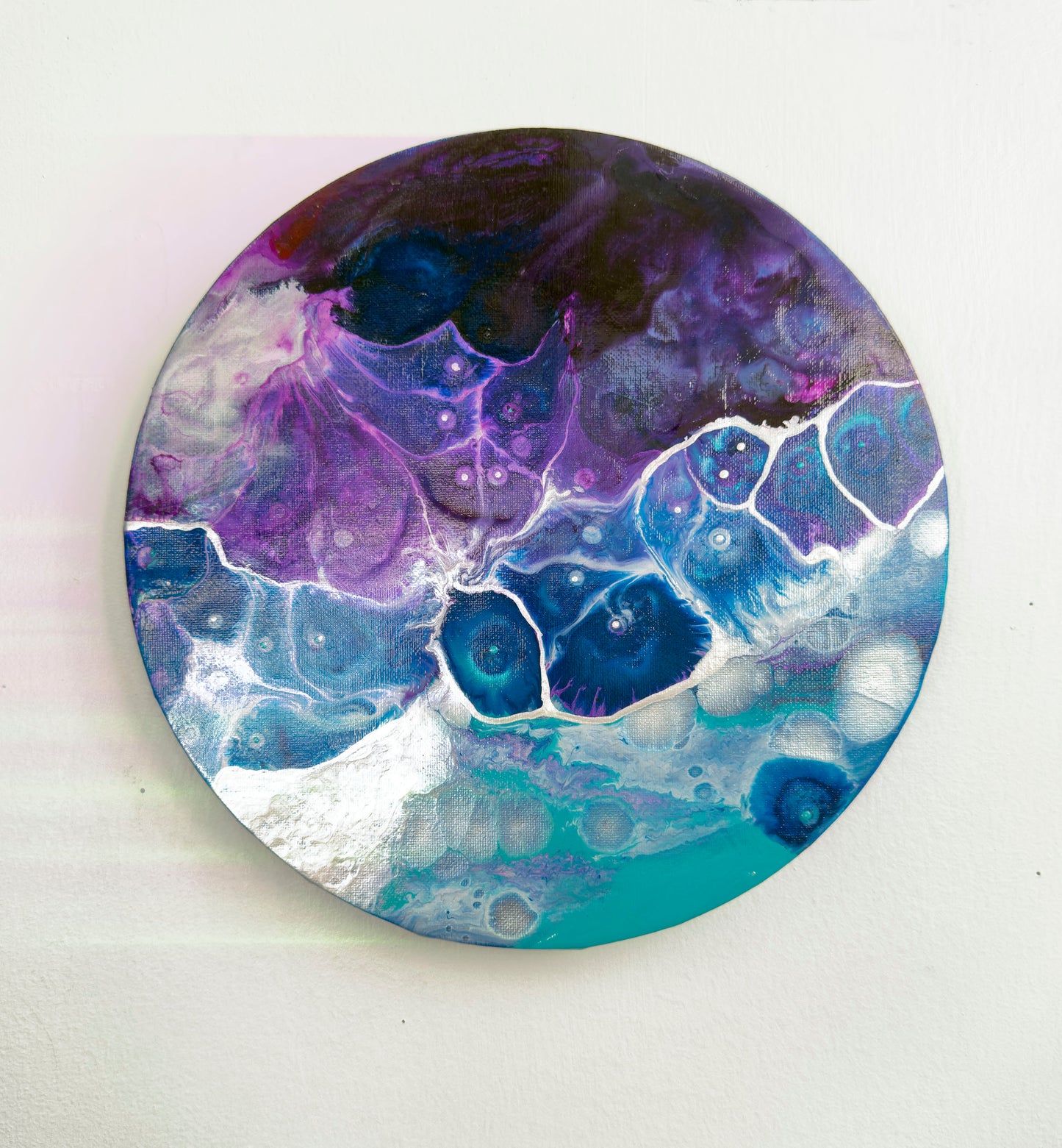 Round decorative wall art, abstract painting with a purple and blue abstract design on a white wall  background