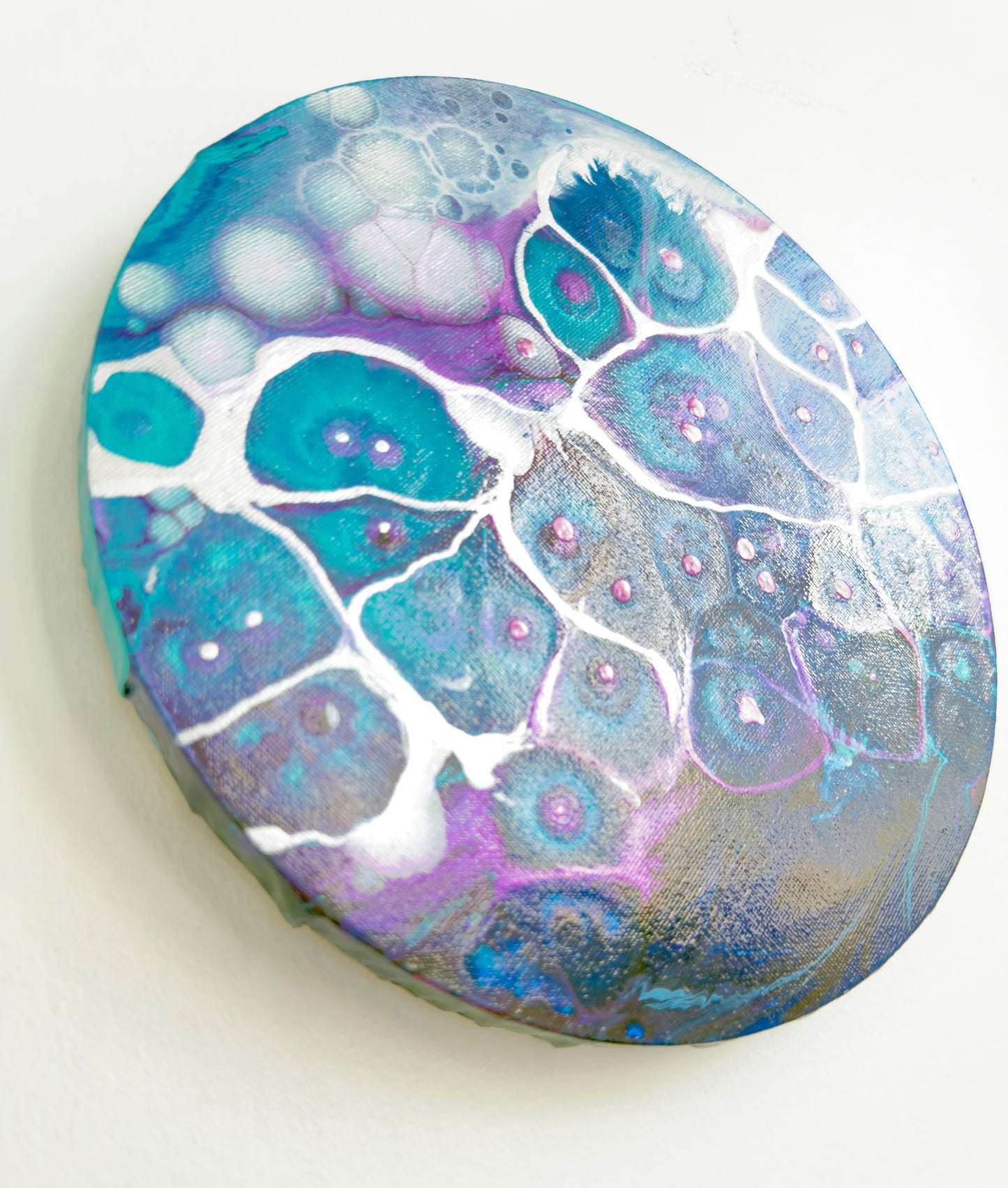 Decorative round wall art with blue, purple, and white marbled pattern on a white background