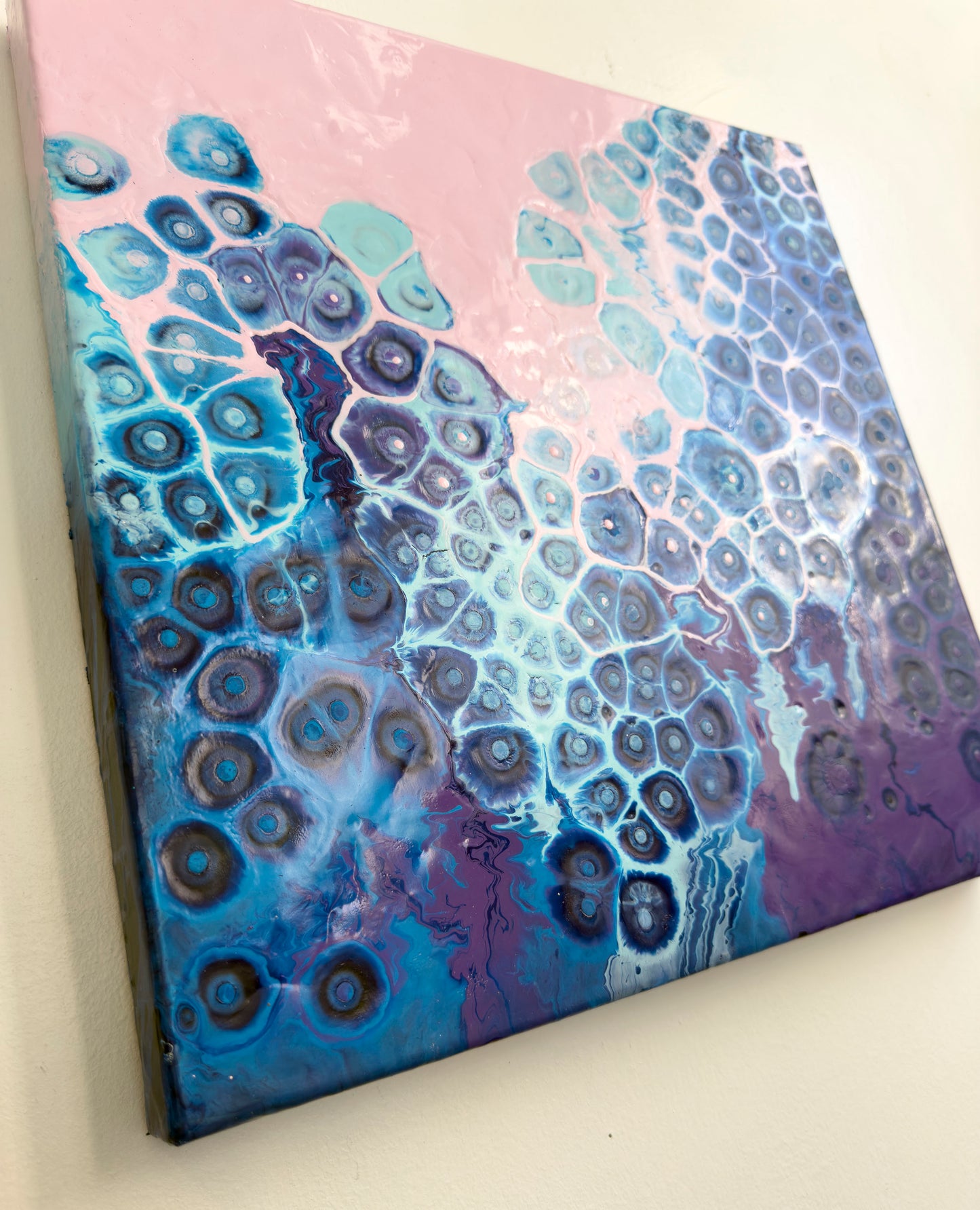 Abstract art piece with blue and purple patterns on a pink background