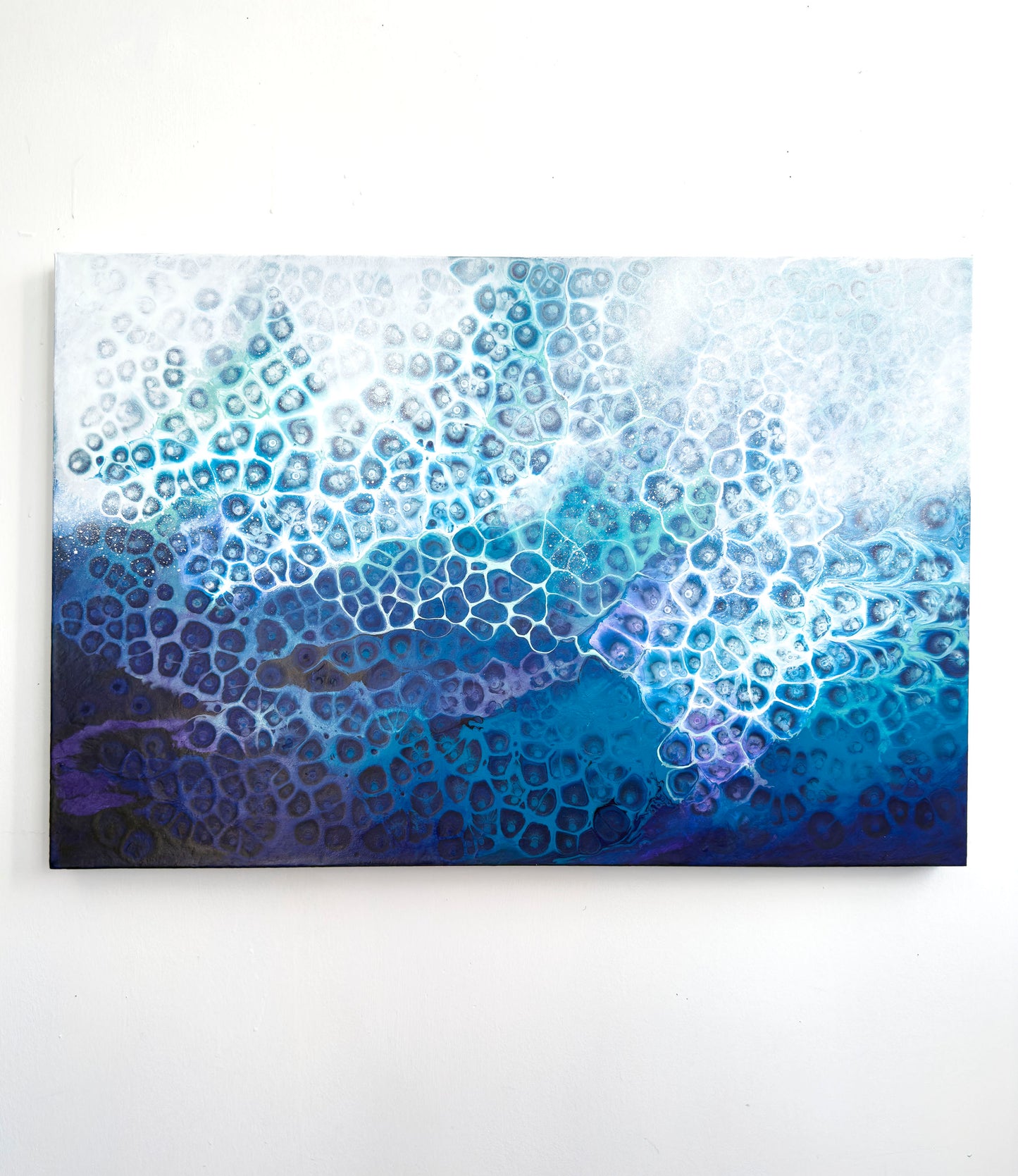 Abstract wall art piece with blue and white patterns on a white background