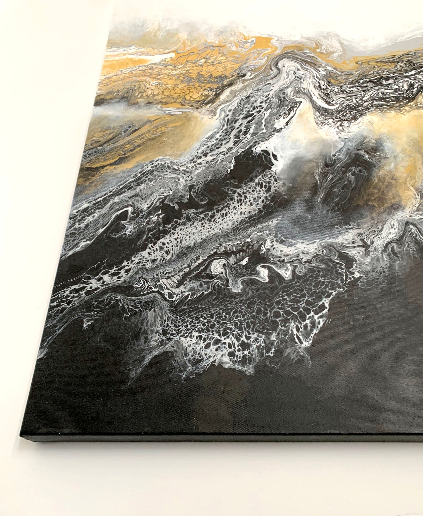 A abstract fluid painting featuring swirls of black, white, and gold colors with a textured and fluid brush stroke technique.