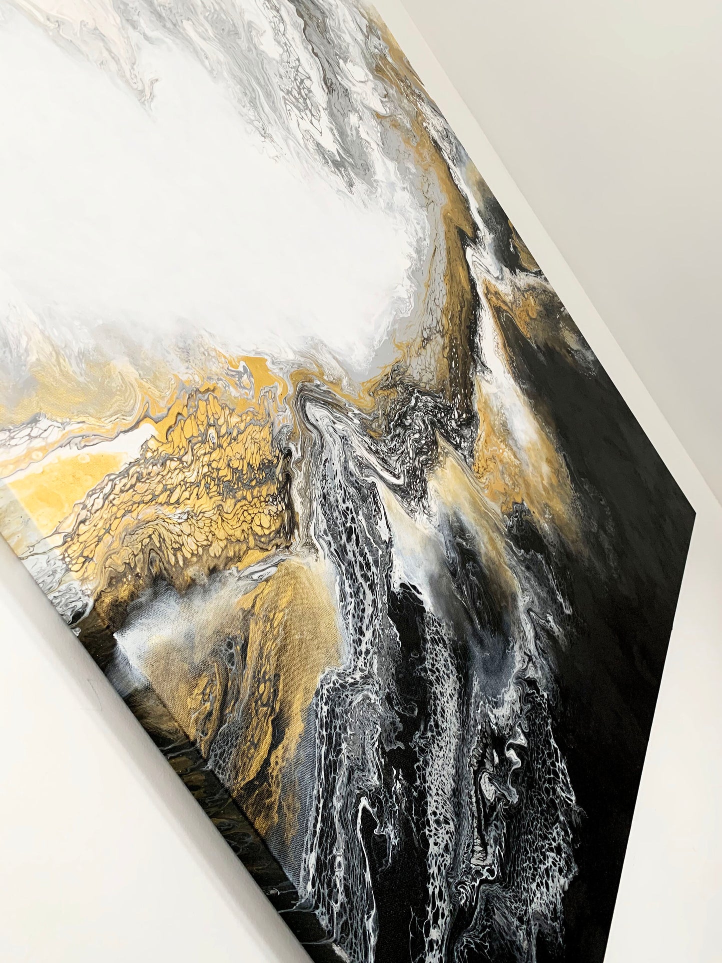 A abstract fluid painting featuring swirls of black, white, and gold colors with a textured and fluid brush stroke technique.